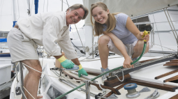 A smiling couple lean into the shot next to their 帆boat.